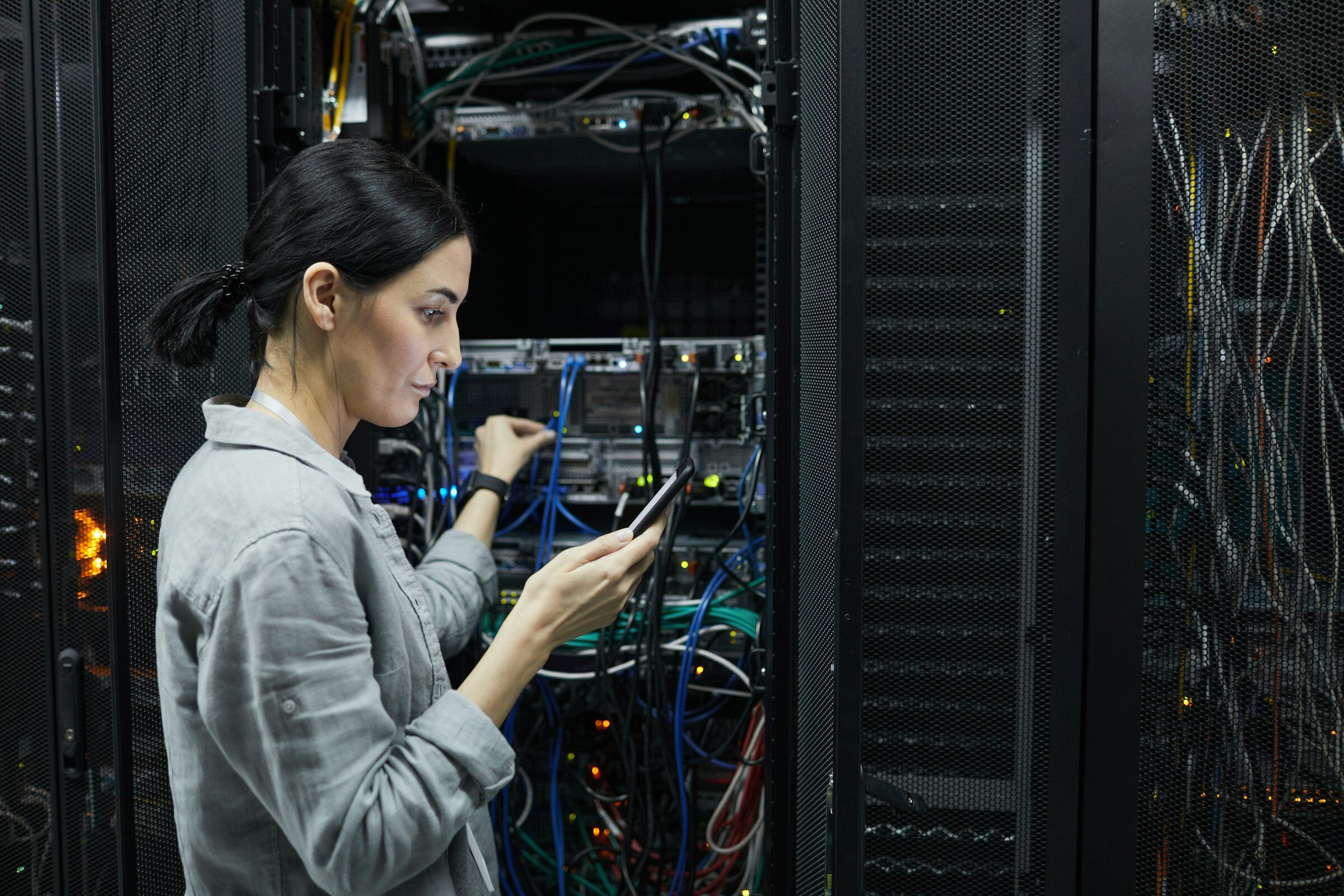 Technician reviewing infrastructure connections in a data center environment, illustrating operational context for SQL Server monitoring.