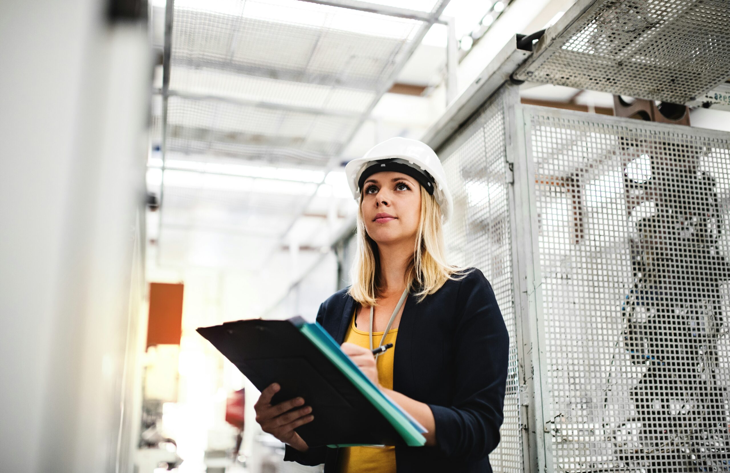 Engineer inspecting industrial equipment with a clipboard during a technical review, representing structured assessment and operational risk evaluation.